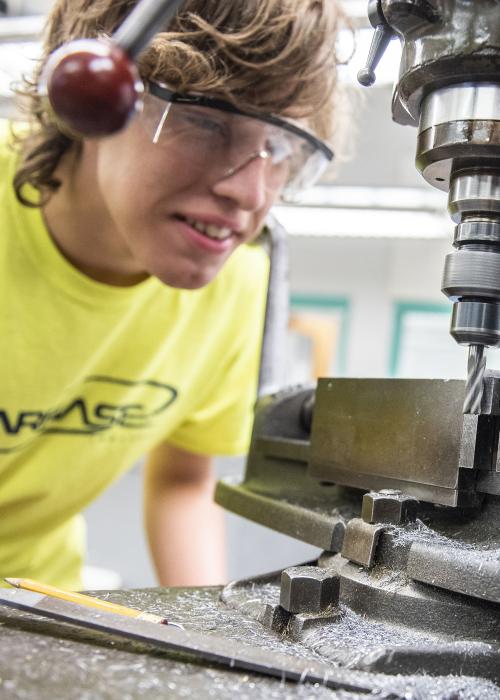A student learning how to use a drill press