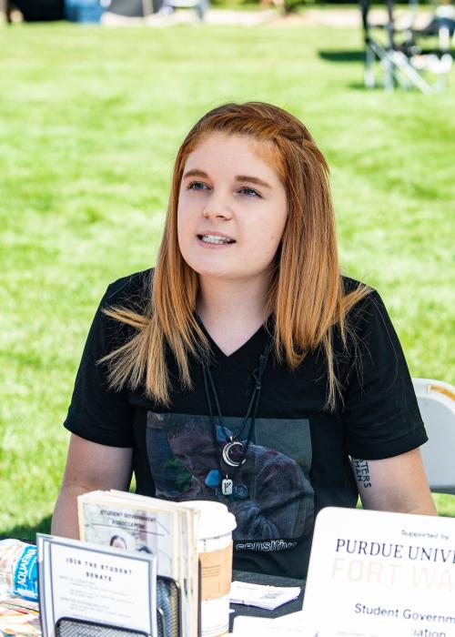 A student talks to a student organization leader at an information table.