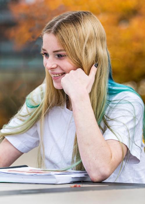 A student studies outside and works on a laptop.