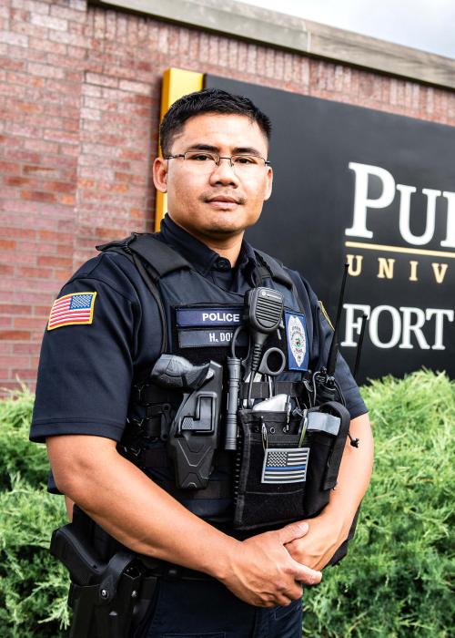 PFW police officer Htoo Doh is standing in front of the Purdue Fort Wayne main campus sign