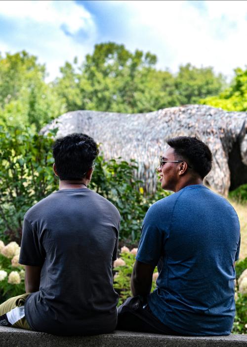 Two students site on a ledge near the Mastodon statue.