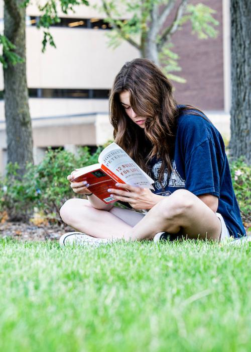 Student reading a book outside.