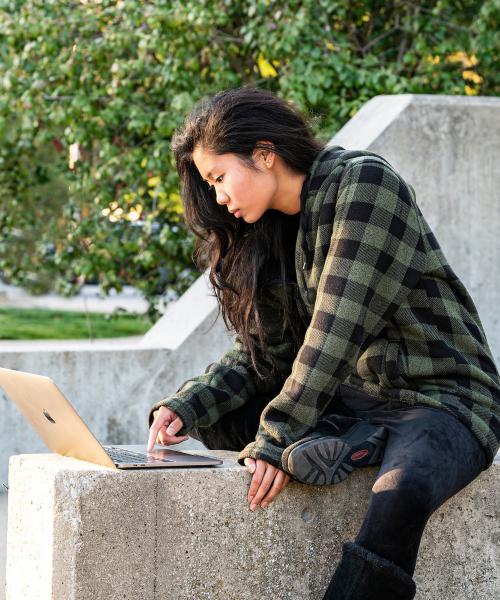 Female student sitting and studying outdoors.