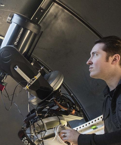 Physics student using a telescope in the observatory lab.