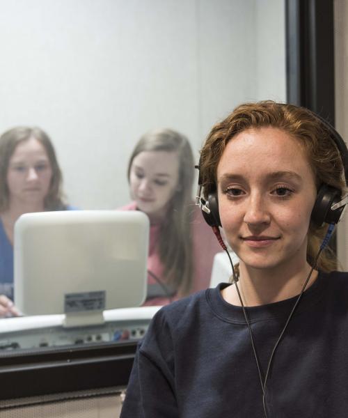 Communication science and disorders students testing a subject's hearing in a mock lab setting.