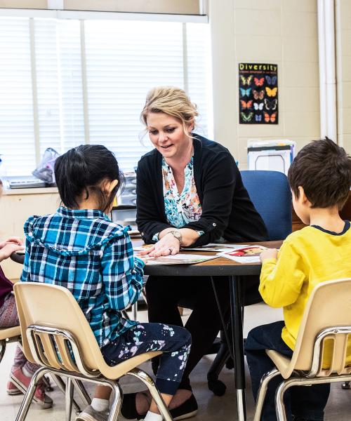 A female teacher at a table of elementary students