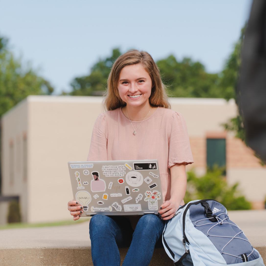 Female student sitting and studying outdoors.