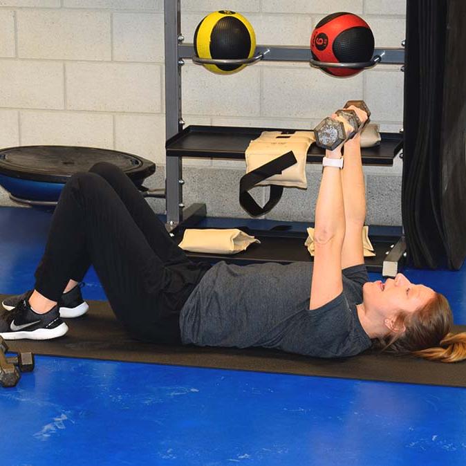 Health coach demonstrating arm press with small weights