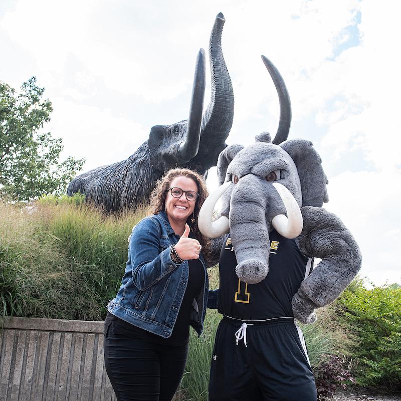 Krissy standing with Don the Mastodon in front of the statue.