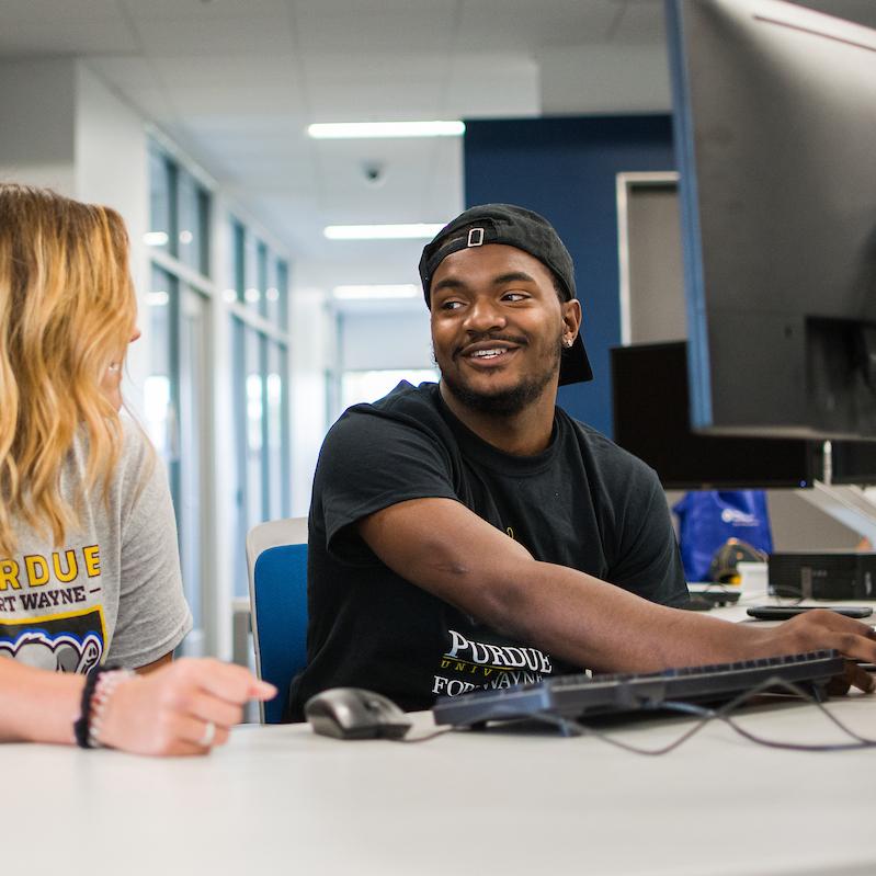 Students working together at a computer in the library.