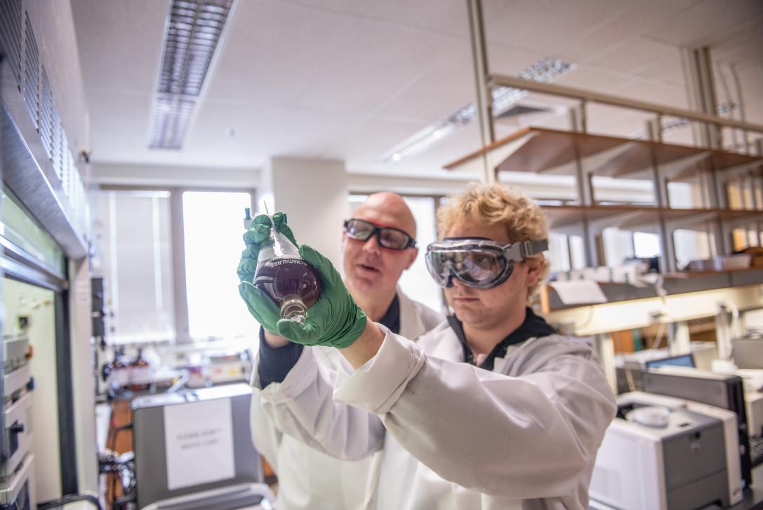 Chemistry student wearing protective goggles and gloves during an experiment.