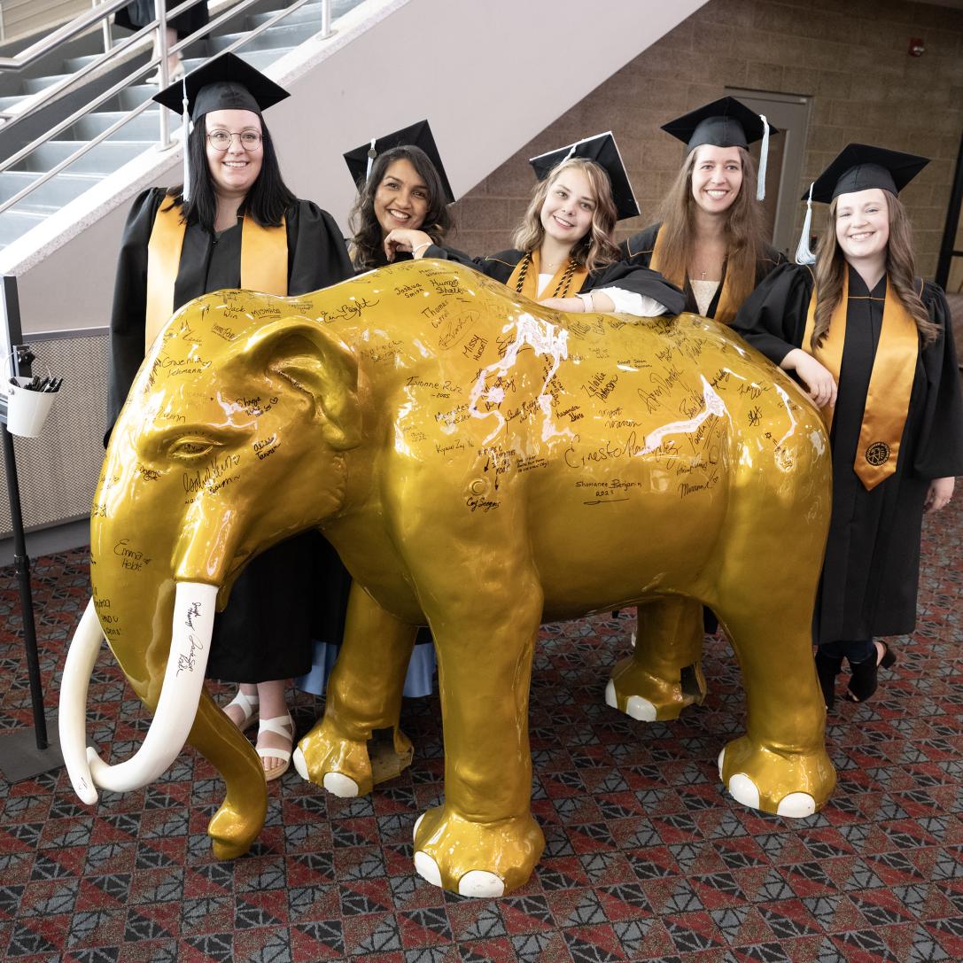 Graduates standing with a mastodon