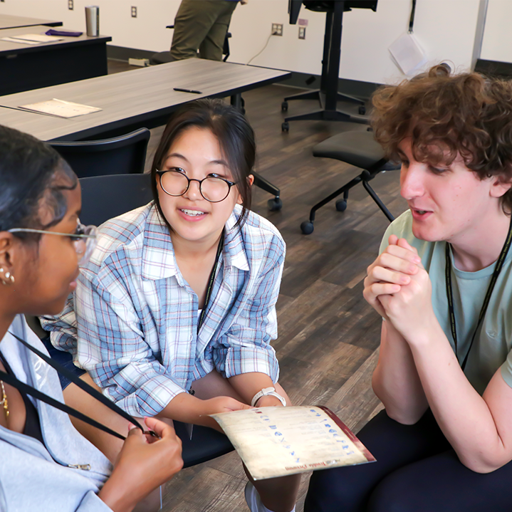 Three students gather to discuss strategy during a Collaboratory game.