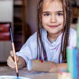 Young girl is painting with a brush
