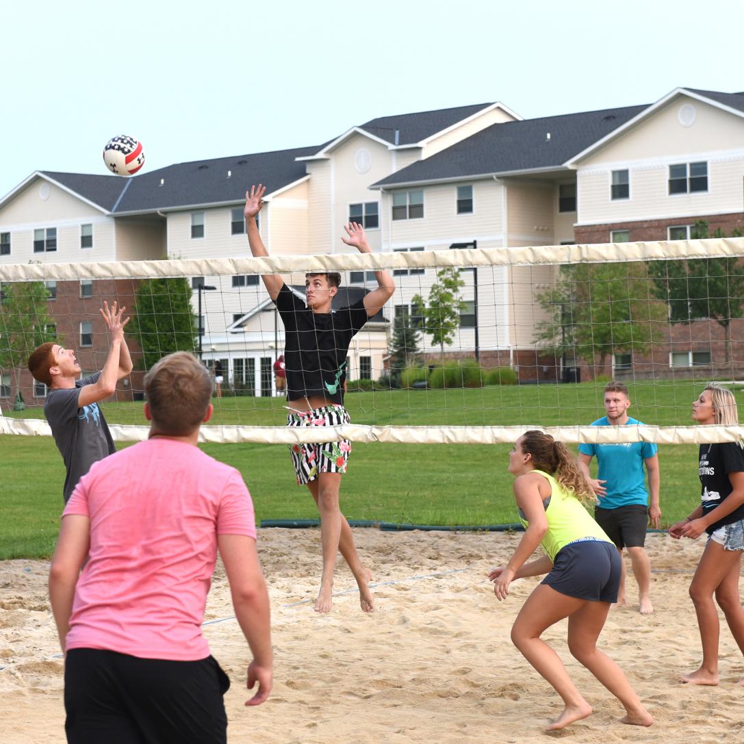 PFW students enjoy a game of sand volleyball on the campus of Student Housing.