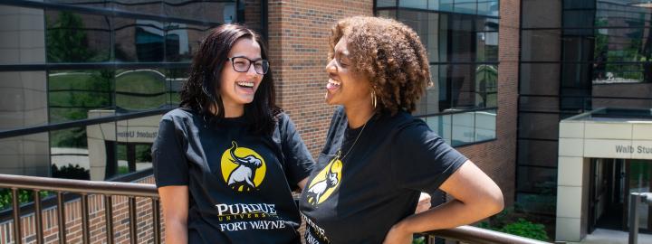 Two transfer students stand outside wearing PFW Transfer shirts.