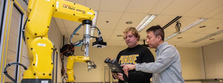 Student works in an engineering lab with a robotic arm.