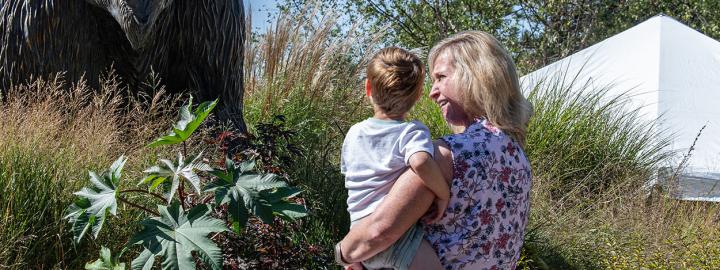 An employee and her child admire the bronze mastodon statue on the Alumni Plaza.