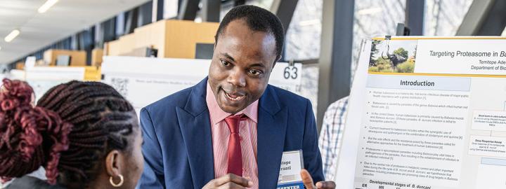 A student explains his research project to a judge at the symposium