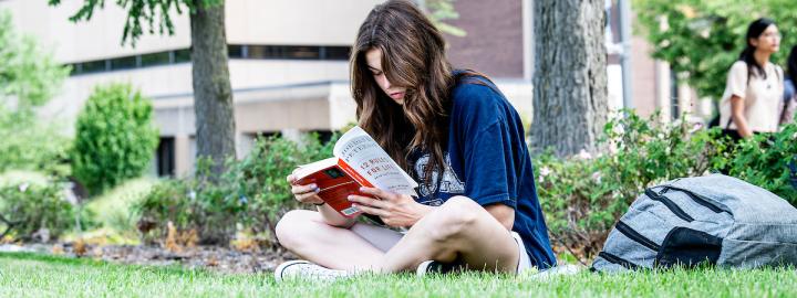 Student reading a book outside.