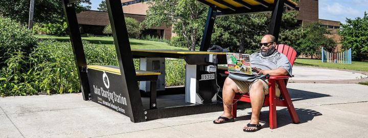 Buck Jordan is working on his computer at the outdoor solar charging station