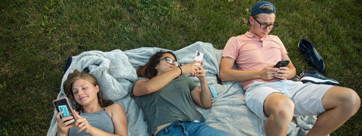 Students on the lawn read Don Life newsletter on their phones.