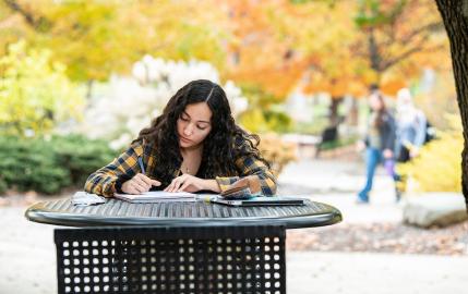 Student studying at a table outside during the fall.