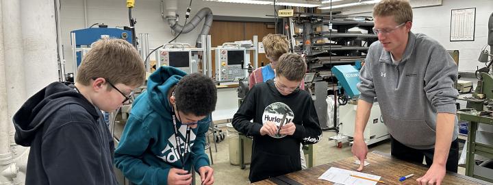 Middle school students working on mechanical engineering activities at a work station