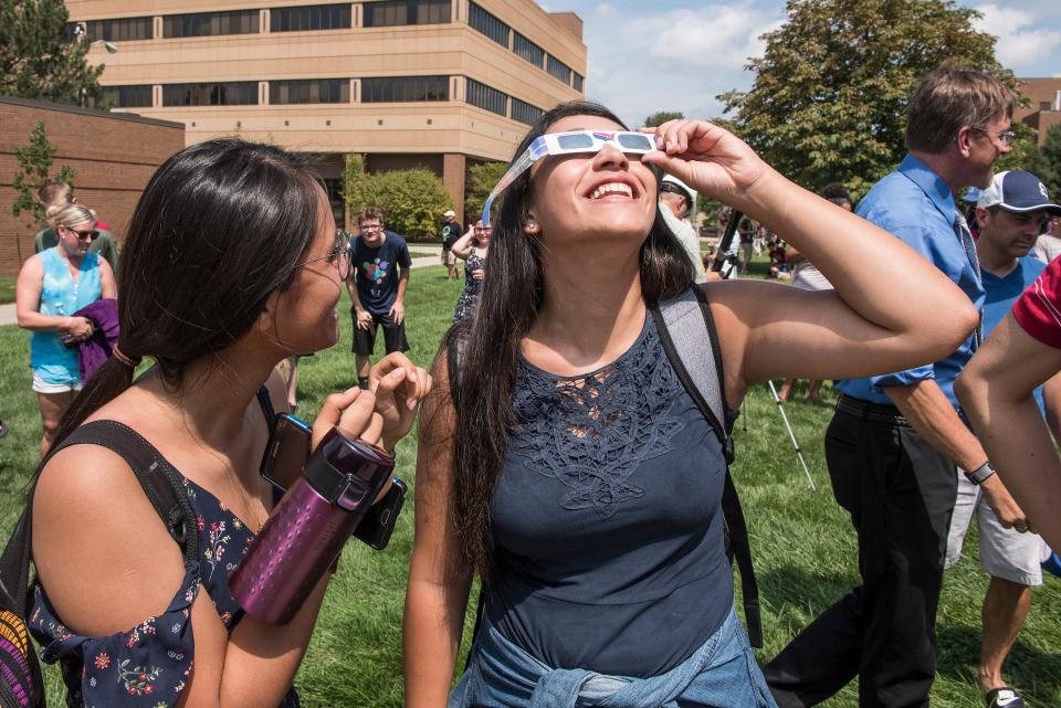 Students use glasses to look at an eclipse.