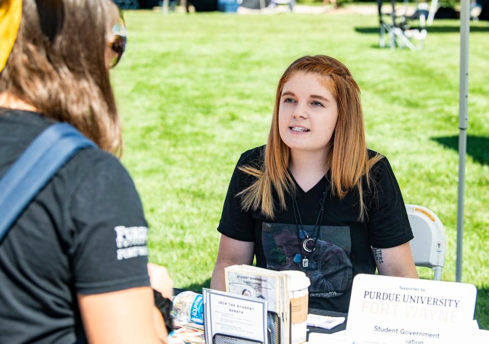 A student talks to a student organization leader at an information table.