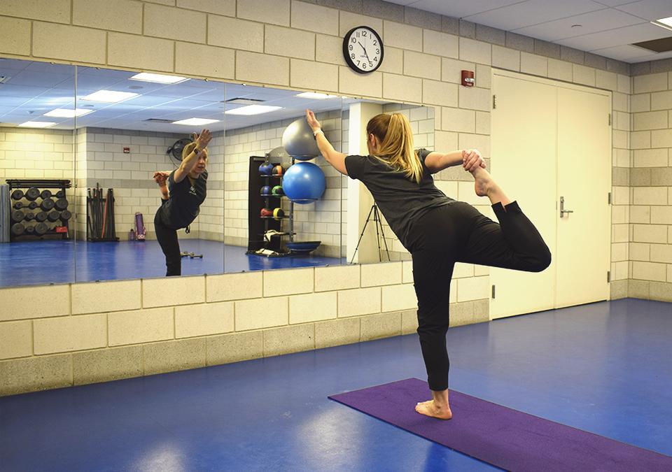 Employee Yoga class instructor demonstrating a standing balance pose