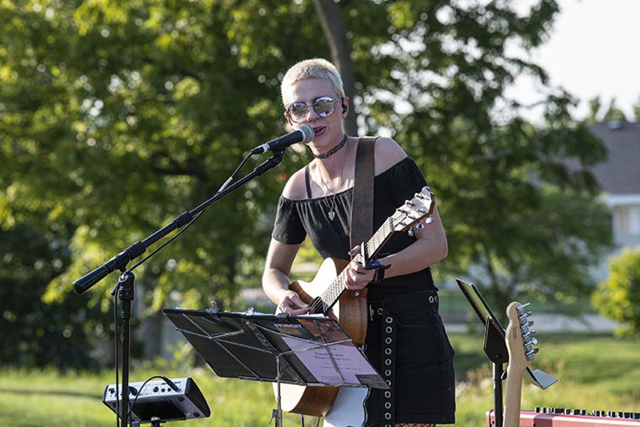 A woman plays an instrument and sings into a microphone.