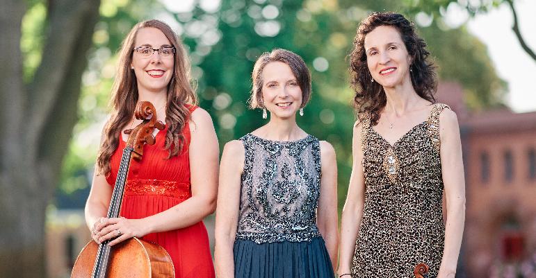 three women smiling wearing fancy dresses