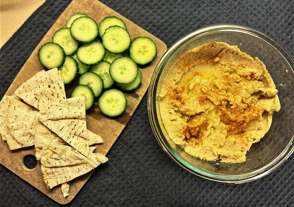 Garlic hummus in a bowl served with cucmber rounds and pita bread slices for Meatless Monday