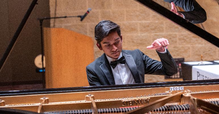 photo of young man playing grand piano