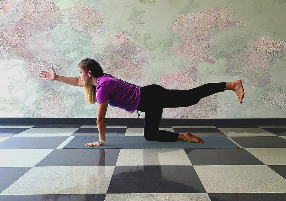 Health coach demonstating the bird dog yoga pose on a gray mat with pastel muted wall in the background and a white and black checkered floor