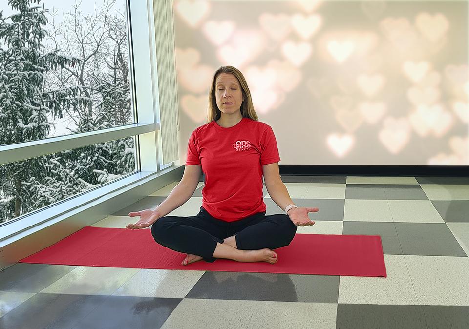 Yoga instructor in red t-shirt for Healthy Heart month showing the seated meditation pose.