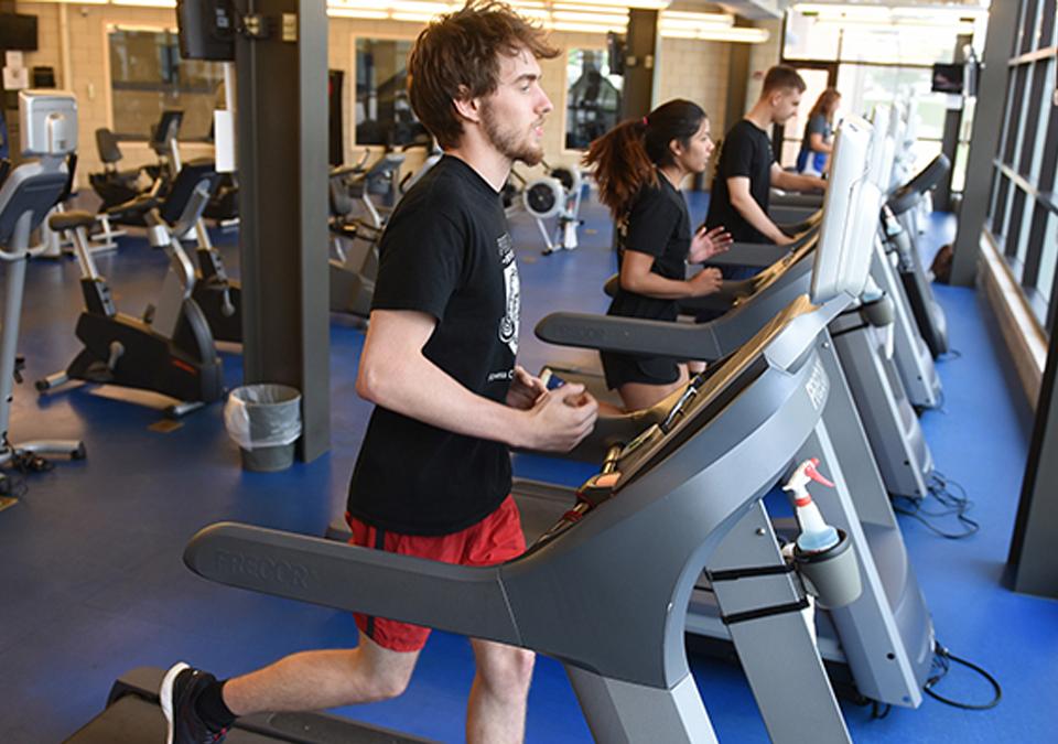 Male and female students working out on treadmills at the Fitness Center