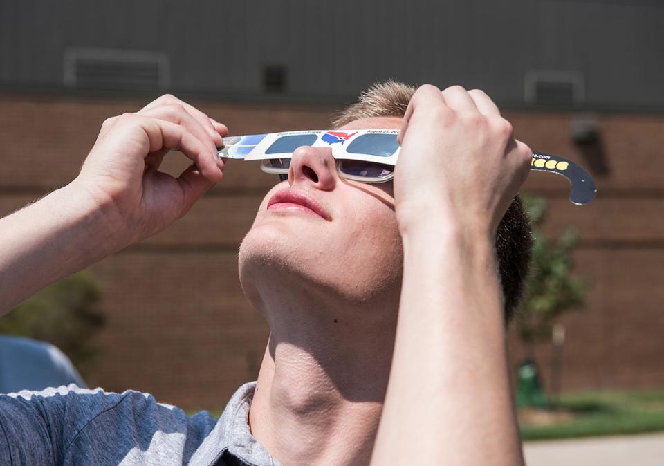 A student is viewing a solar eclipse through special glasses