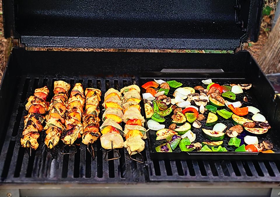 Vegetables and shish kebabs being cooked on a grill