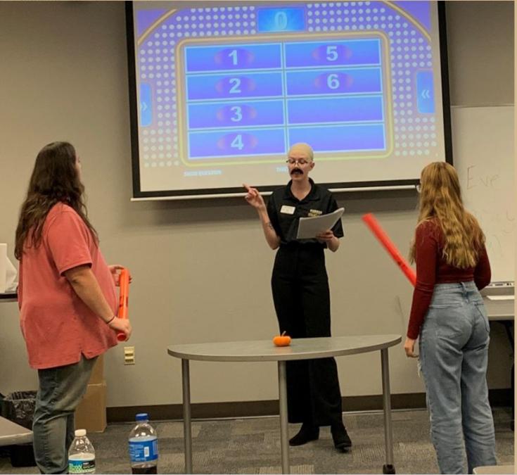 Financial Feud host (wearing bald cap) asking question during game