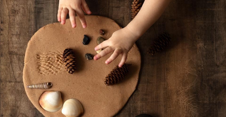child making clay creation with nature objects