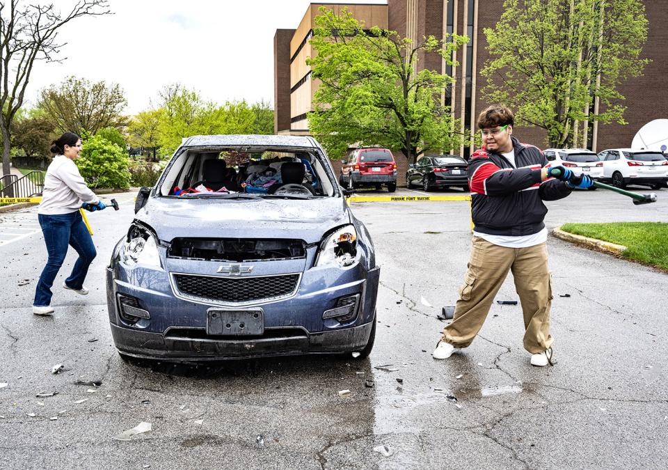 Two students are smashing a car with sledgehammers