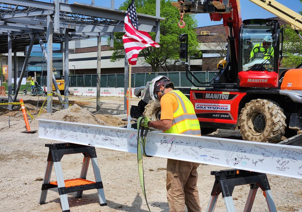 A construction worker readies the autographed beam before it is hoisted to the top of the building.