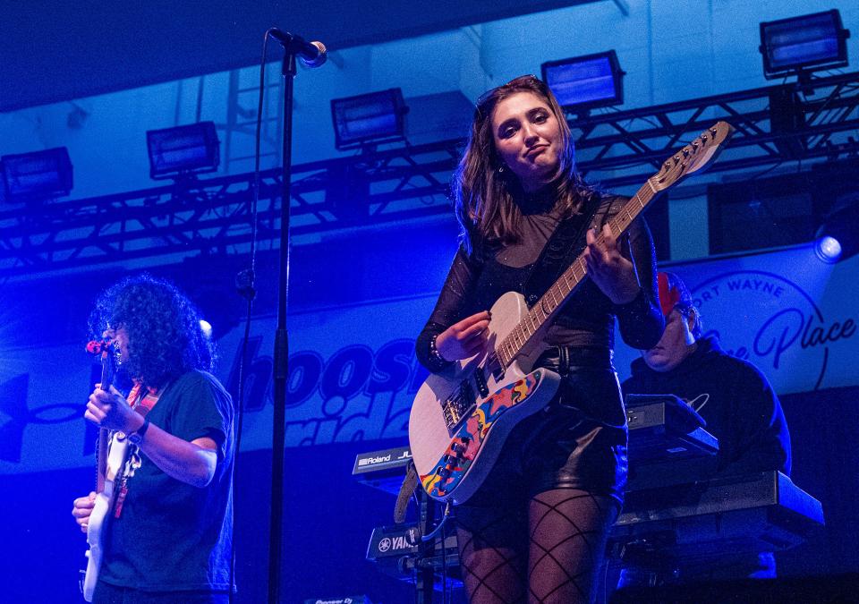 Hailee Richmond is playing guitar while performing with a band