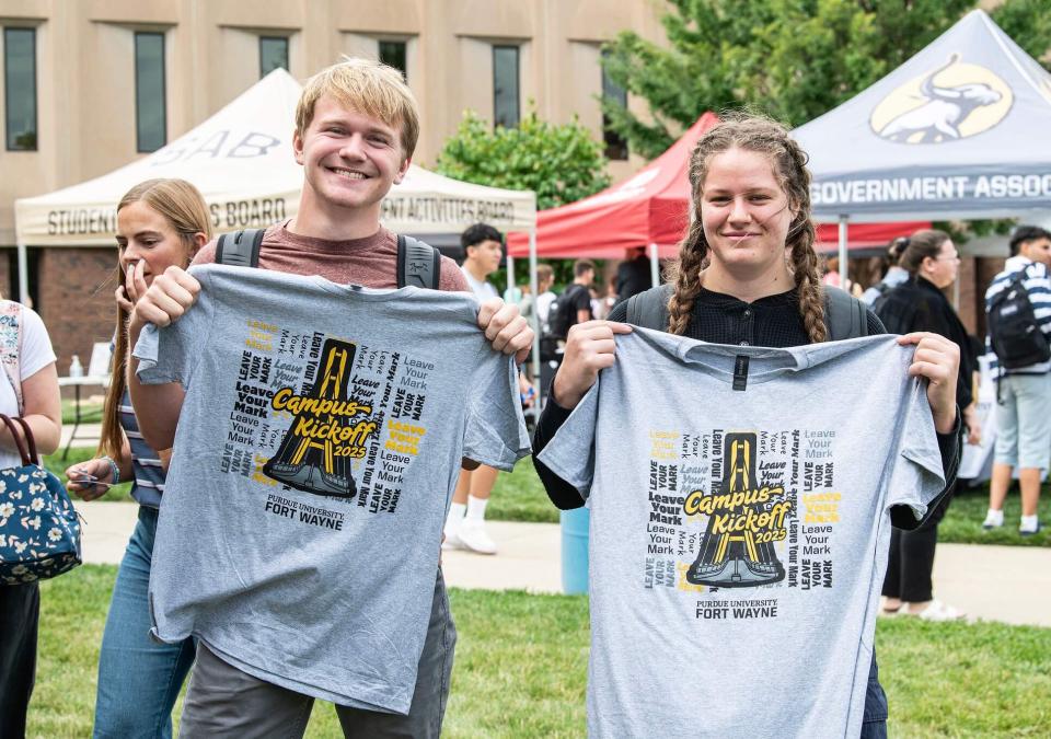 Two students are displaying campus kickoff t-shirts