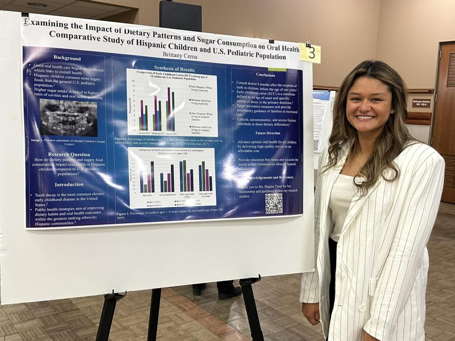 Undergraduate female student standing by poster
