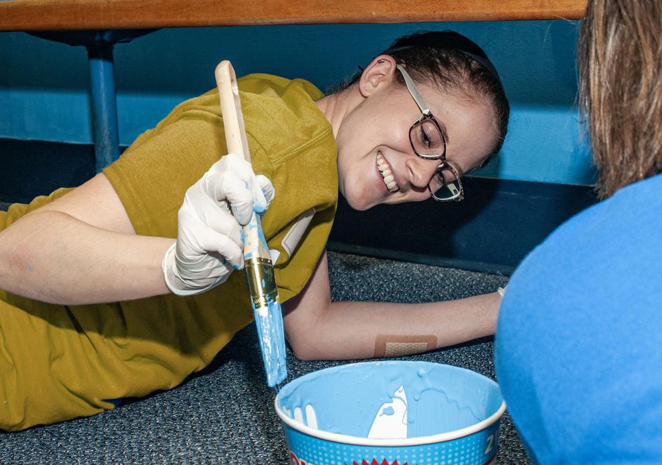 A student is painting while taking part in community service.