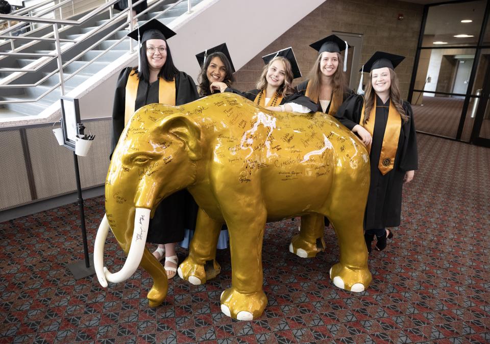 Graduates standing with a mastodon