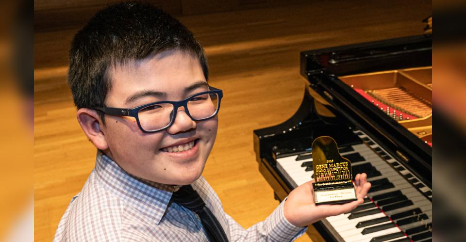 child holding trophy next to piano